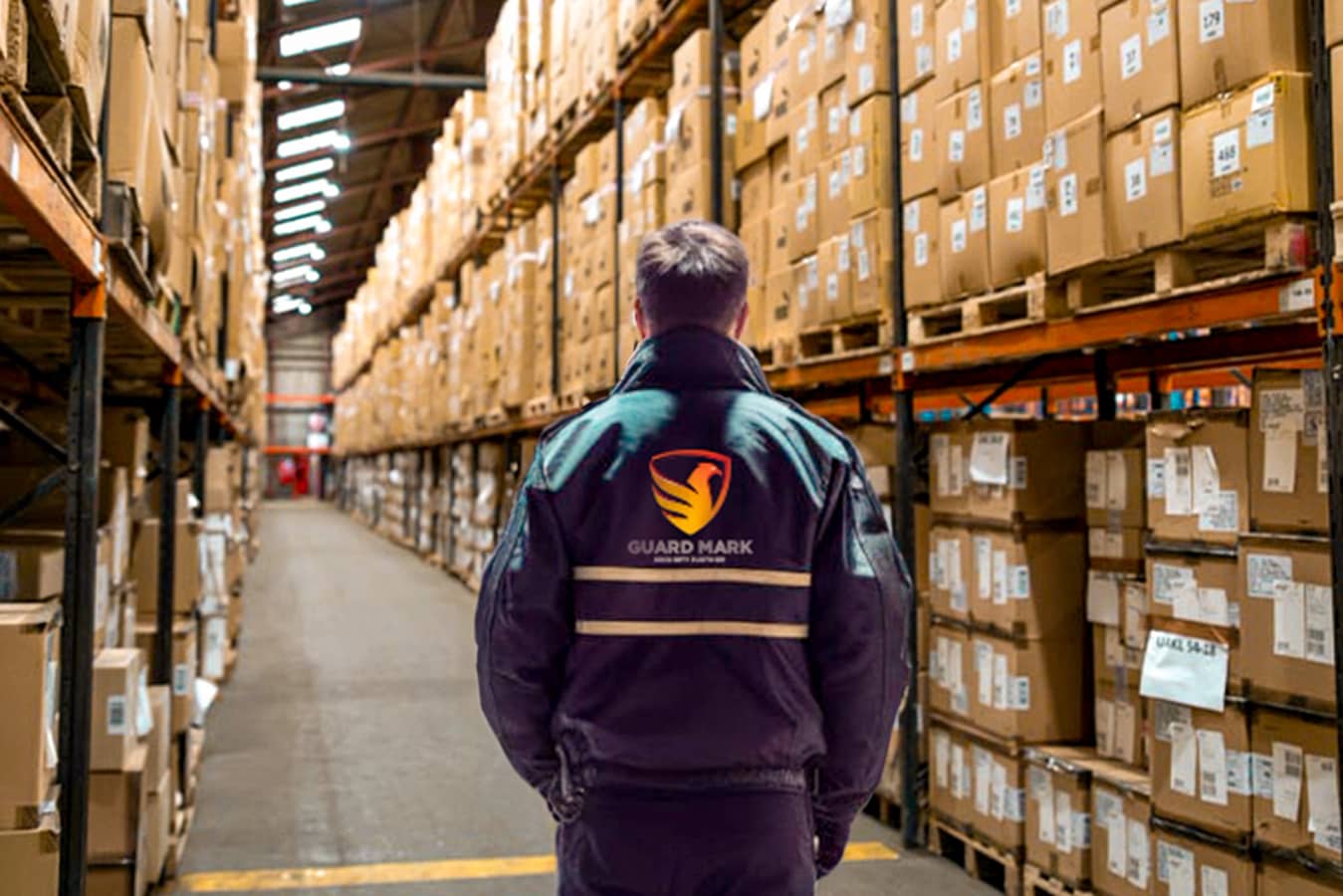 Security guard in Guard Mark uniform performs duties at warehouse or production site, ensuring safety and security.