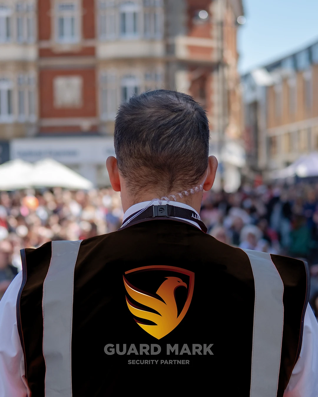 UK event security Guard in Guard Mark uniform performs duty, manages anti-social behavior, maintains safety professionally.